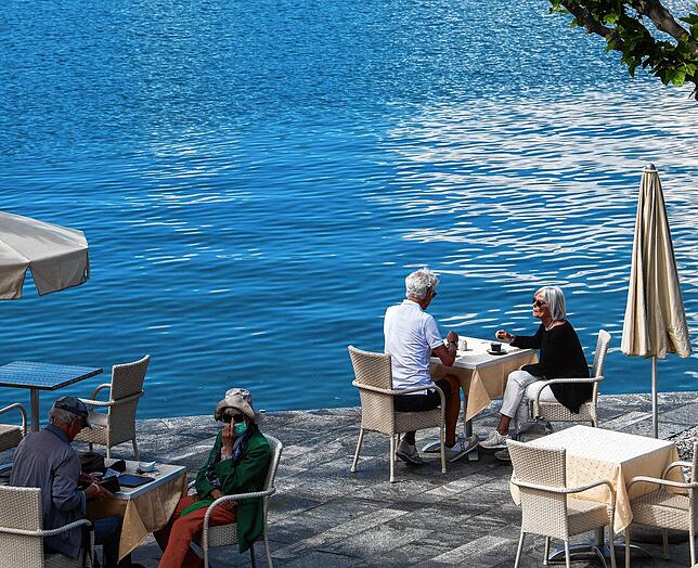 Einheimische und Touristen genießen das sonnige Wetter an der Uferpromenade am Schweizer Ufer des Lago Maggiore. In kein anderes ...