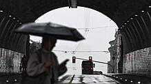 Eine Frau geht am 22. Juli mit einem Regenschirm vor einem Tunnel in Stuttgart. Auch am heutigen Donnerstag drohen Gewitter und Regen.