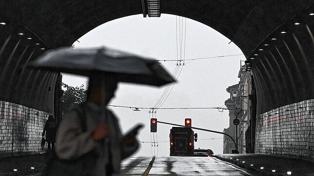 Eine Frau geht am 22. Juli mit einem Regenschirm vor einem Tunnel in Stuttgart. Auch am heutigen Donnerstag drohen Gewitter und Regen.