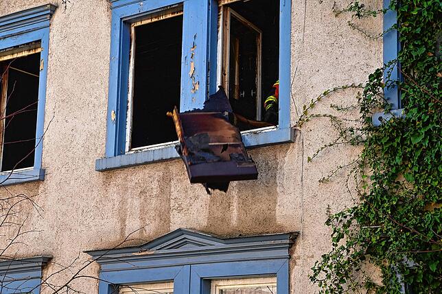Nach dem das Feuer gelöscht ist, entsorgen die Feuerwehrleute das verkohlte Inventar aus der Wohnung.