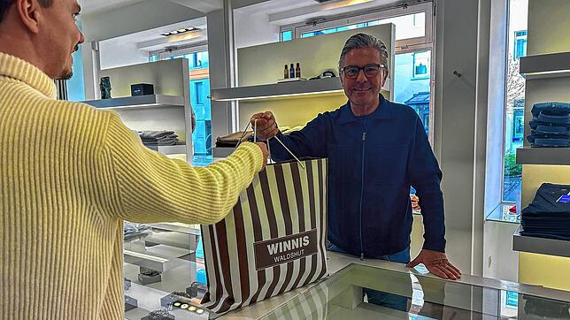 Karlheinz Renz übergibt einem Kunden eine gepackte Einkaufstasche. Zum Black Friday gibt es besondere Angebote.