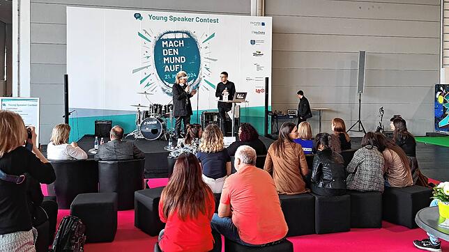 Auf der Bühne beim Young Speaker Contest in der Jugendhalle der IBO 2024 spricht der 18-jährige Tom Lucas Siller (rechts) aus ...
