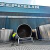 Markus Vöge vor riesigen Bauteilen im Hof von Zeppelin Systems in Friedrichshafen.