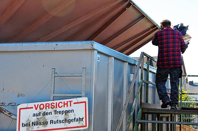 Ein Mann entsorgt Abfall in einem Container auf dem Recyclinghof.