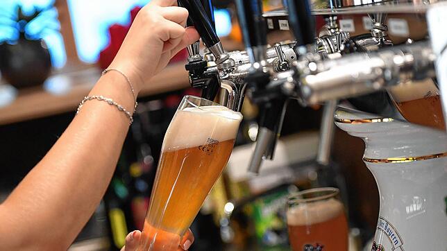 Eine Bedienung zapft Bier in einem Wirtshaus. Die Gasthaus-Rechnung könnte demnächst teurer werden. In der Branche werden Aufschläge für ...