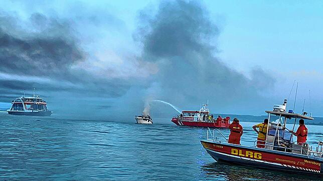 Das Feuer auf dem Motorboot ist fast gelöscht. Im Hintergrund ist die Autofähre zu sehen, im Vordergrund ein Boot der DLRG.