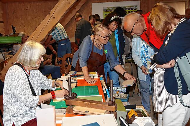 Besucher des Handwerkstages lassen sich bei den Buchbindern zeigen, wie diese arbeiten.