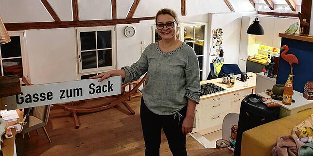 Sandra Fuchs in ihrer „Wohnhalle“ neben dem selbst entworfenen neuen Namensschild für die Gasse, in der sie wohnt.