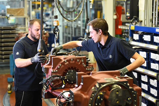 Zwei ZF-Mitarbeiter in Passau bei der Montage der Elektroportalachse „AxTrax AVE“ von ZF: Zwei Motoren mit je 125 kW ...