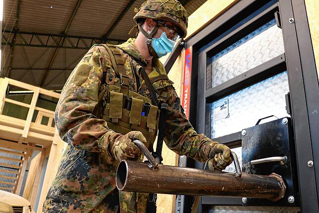 Soldat mit Ramme. Manchmal muss der Stahltür mit brachialer Kraft getrotzt werden.