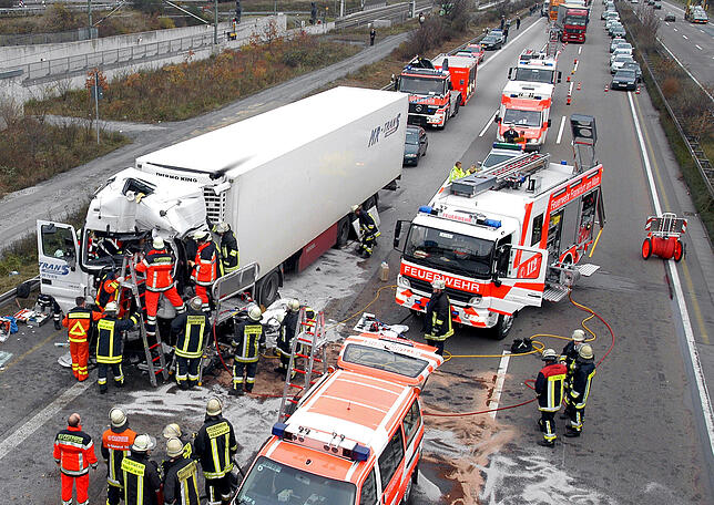 Rettungskräfte bemühen sich einen in seinem Führerhaus eingeklemmten Lkw-Fahrer zu befreien.