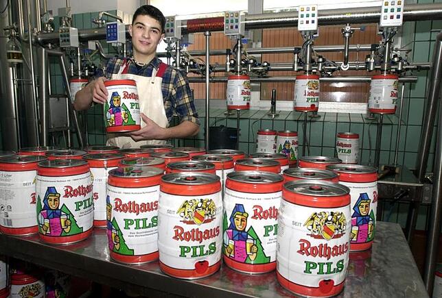 Ein Mitarbeiter der Rothaus-Brauerei stapelt 5-Liter-Bier-Fässchen.