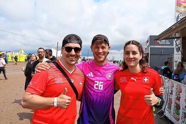 Arm in Arm mit einem Deutschlandfan zeigen sich die Schweizer Lionel und Patricia.
