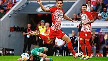 Der Augsburger Ruben Vargas Martinez (l) blickt am Boden liegend zum Ball, während er vom Freiburger Yannik Keitel übersprungen wird.