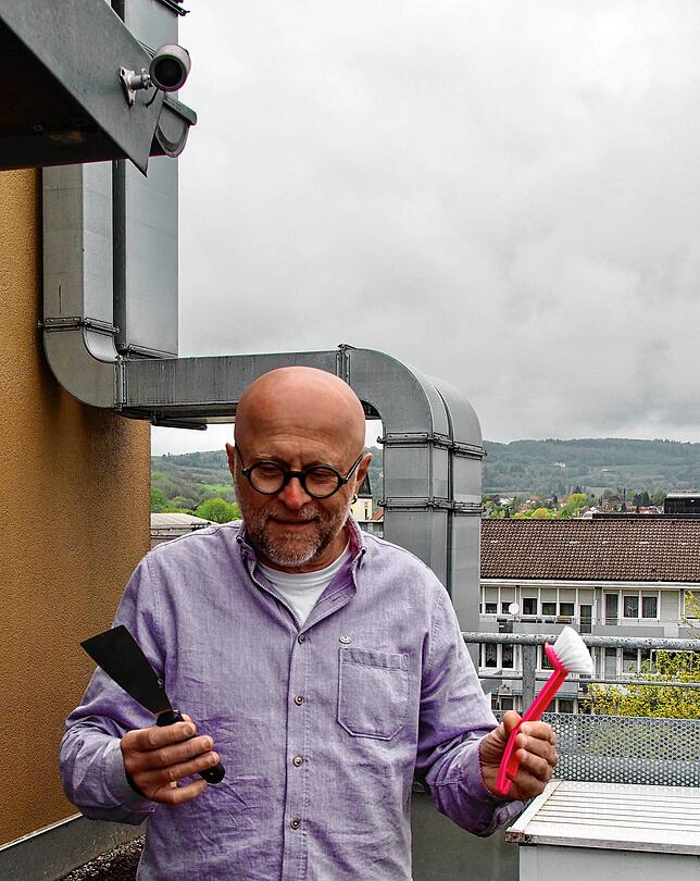 Rainer Klose geht mit Bürste und Spachtel gegen den Taubendreck auf seiner Dachterrasse vor. Über ihm hängt ein Ultraschallgerät zur ...