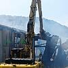 Ein Bagger räumt die Dachteile, die auf dem Brandschutt liegen, damit die Feuerwehrleute die letzten Glutnester löschen können.