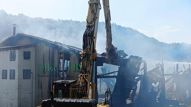 Ein Bagger räumt die Dachteile, die auf dem Brandschutt liegen, damit die Feuerwehrleute die letzten Glutnester löschen können.