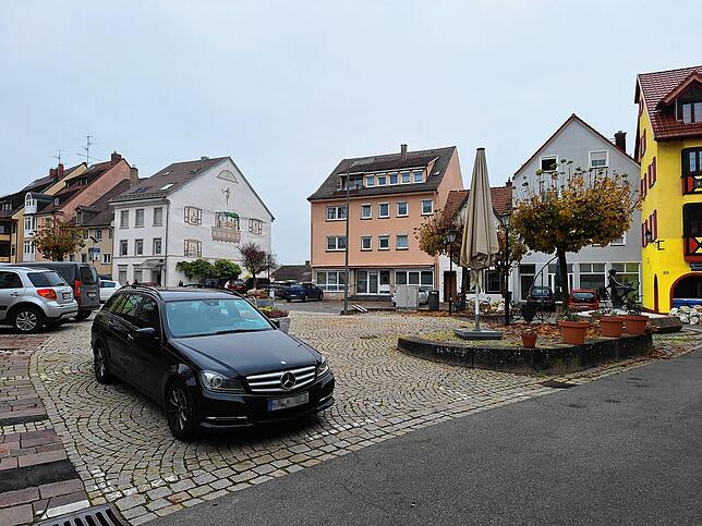 Blick auf den Gustav-Hammer-Platz: Hier – auf der Fläche zwischen dem geparkten schwarzen Auto und den Bäumen mit dem Brunnen rechts – ...