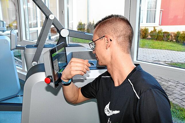 Marc Sieber liest am Trainingsgerät die auf seinem Armband hinterlegten Daten für die Sporttherapie ein.