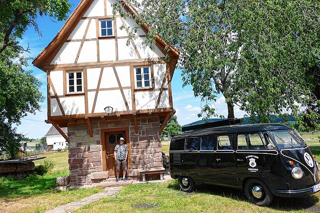 Bertram Merz lehnt lässig vor seinem Lustschloss und blickt auf den Festplatz. Neben seinem Herrschaftssitz steht der schwarze ACE-Bus, ...