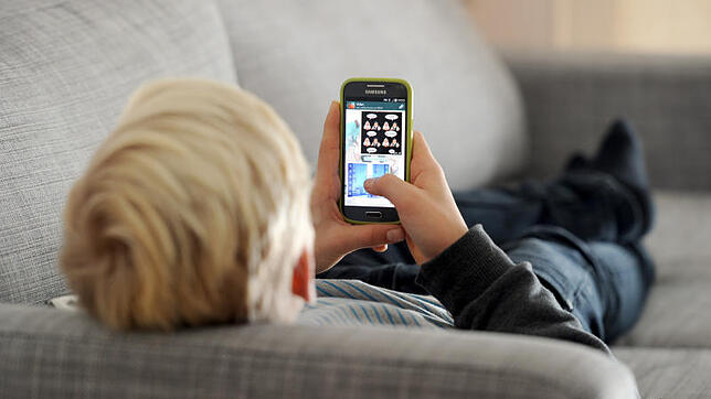 Typische Haltung vieler Jugendlicher: Entspannt mit dem Smartphone spielen oder mit anderen chatten.