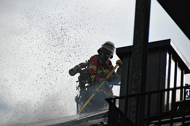 Feuerwehrleute öffnen den Dachstuhl, um die Flammen im Inneren bekämpfen zu können.