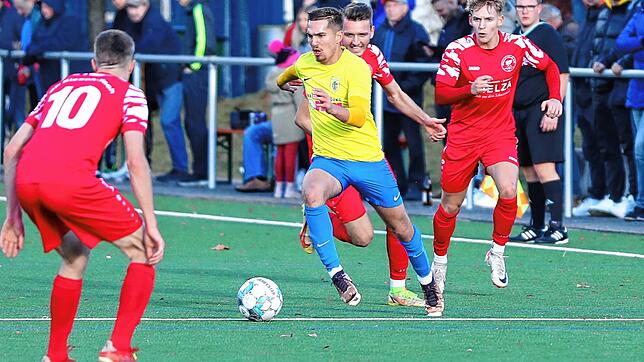 Der Singener Marcel Ernst (Mitte) behauptet den Ball gegen seine Gegenspieler vom SF Elzach-Yach (rot).