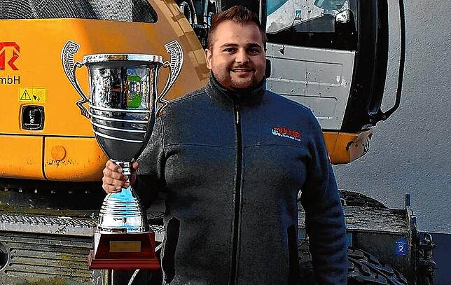 Robin Müller ist zweimaliger Europameister im Baggerfahren. Hier zeigt er stolz seinen EM-Pokal.
