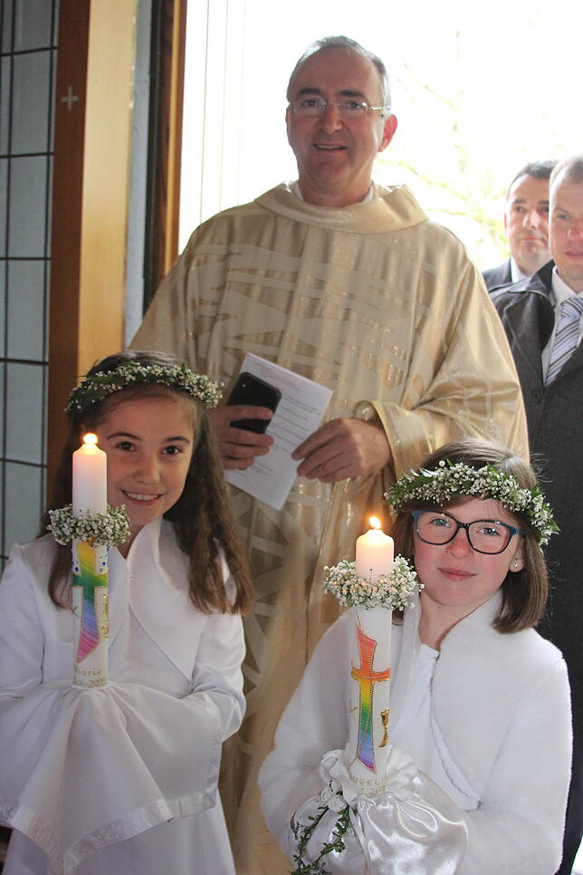 Zwei Mädchen feierten in der Pfarrkirche St. Sebastian in Aichen feierten ihre Erstkommunion. Im Bild Pater Christoph mit links Marie ...