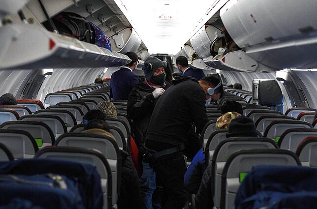 Passagiere steigen mit Mundschutz in ein Flugzeug.