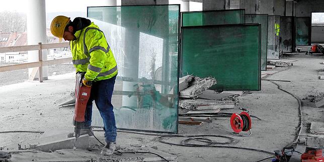 Schweres Gerät im Einsatz: Ein Abbrucharbeiter zerkleinert eine Betonplatte. Die ausgebauten Glasscheiben werden später an der Fassade ...