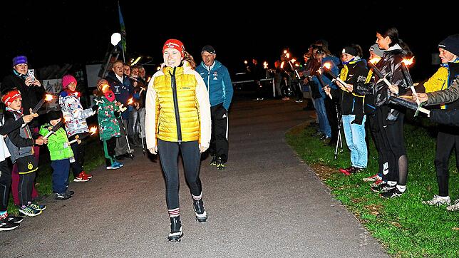 Die Spitzenbiathletin Janina Hettich geht strahlend durch das Fackel-Spalier, das von den jungen Nachwuchsbiathleten gebildet wird.