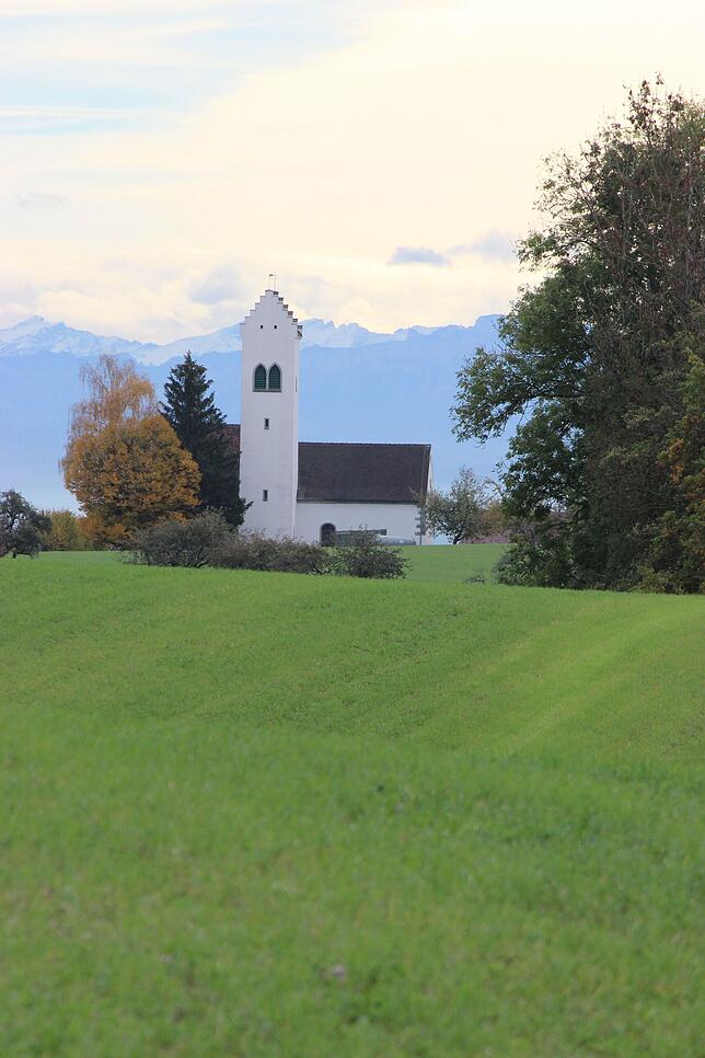 Aufkirch, wie man es liebt: Blick über den Kirchturm hinweg aufs Alpenmassiv.