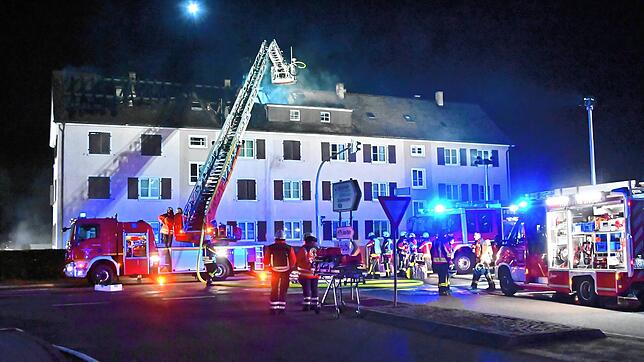 Der linke Teil des Mehrfamilienhauses hat ein ausgebranntes Dachgeschoss. Das Licht über dem Haus ist eine Drohne der Feuerwehr, die mit ...