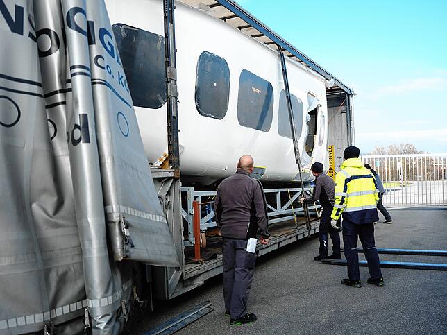Unter der Lastwagenplane kommt die neue Zeppelingondel zum Vorschein.