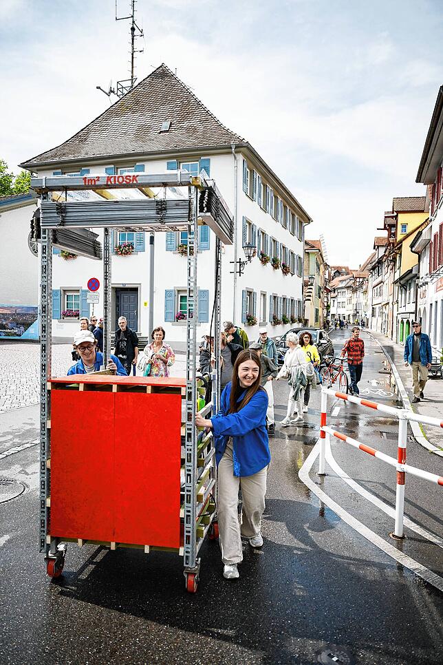 Mit einem fahrbaren Kiosk aus Abfallmaterialien sind Daniel Koller und Maria Covrig (blaue Jacken) auf dem Weg zum Kramer Areal.
