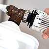 Eine Frau dreht am Thermostat einer Heizung. Es gibt aber noch deutlich mehr Wege, beim Heizen zu sparen.