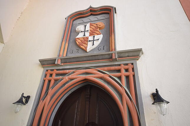 Der Eingang zur Schlosskapelle vom Schlosshof aus mit Wappen über der Tür.
