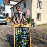 Laura Albrecht steht hinter einem Hinweisschild auf ihre Eisdiele – auch diese Schilder hat sie wie die Speise- und Visitenkarten selbst ...