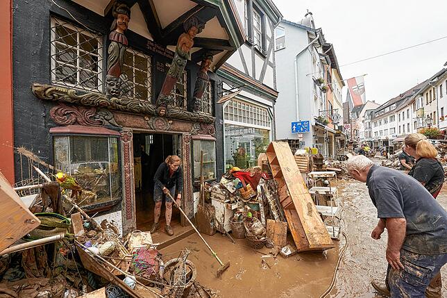 Anwohner und Ladeninhaber in Ahrweiler versuchen, ihre Häuser vom Schlamm zu befreien und unbrauchbar gewordenes Mobiliar nach draußen ...
