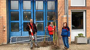 Christoph und Susi Banholzer (von links) holen sich bei Irene Schnarz von der Naturschutzgruppe ihren Baum ab. Bild: M. Stoll
