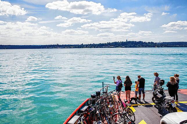 Die Passagiere einer Fähre stehen auf der Strecke zwischen Meersburg und Konstanz am Bug des Schiffes. Die Bodenseeregion soll ...