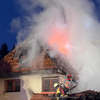 Über die Drehleiter, vom Dach einer Garage und von einer Tragleiter aus bekämpfen Feuerwehrleute am Sonntagmorgen das Feuer in dem ...