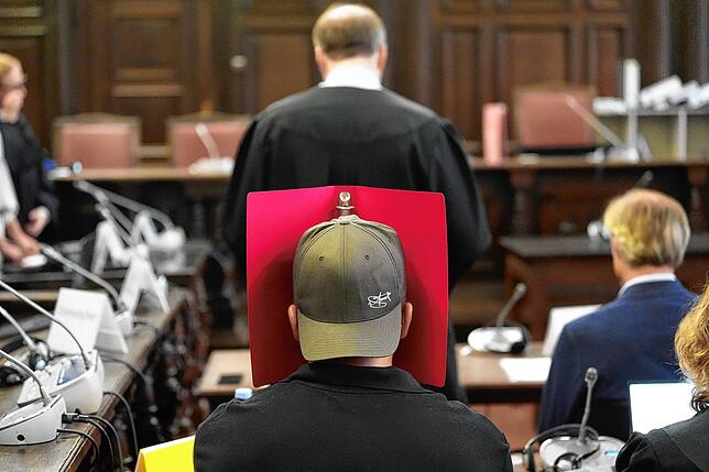 Der Angeklagte P. sitzt im Gerichtssaal im Prozess wegen mutmaßlicher Kindesentführung im Landgericht Hamburg und verdeckt sein Gesicht.