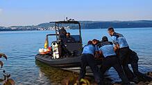 Mit vereinter Kraft schieben die Beamten das Boot der Taucher ins Wasser. Dort markiert eine Boje die Fundstelle der Leiche.