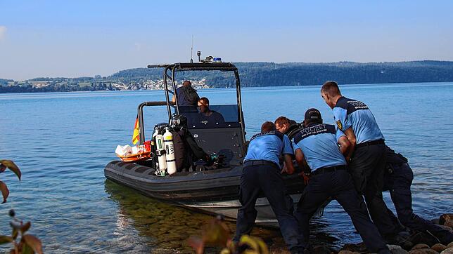 Mit vereinter Kraft schieben die Beamten das Boot der Taucher ins Wasser. Dort markiert eine Boje die Fundstelle der Leiche.
