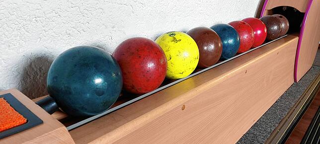 Die bunten Kugeln liegen bereit, um im Spiel möglichst alle Kegel umzuwerfen.