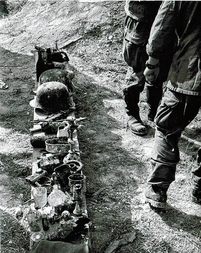 Stahlhelm, Feldflaschen, Lederzeug, Blechtassen, Signallampe: Die Soldaten sammeln Ausrüstungsgegenstände vor dem Stollen.