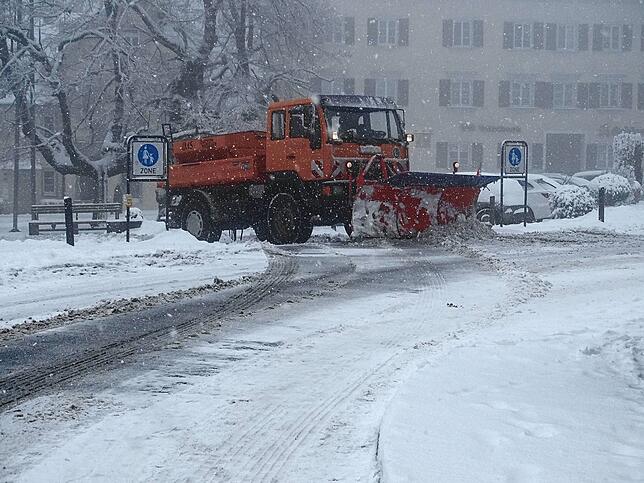 Ein Schneepflug schafft am Parkplatz an der zentralen Bushaltestelle in Heiligenberg den Schnee zur Seite.