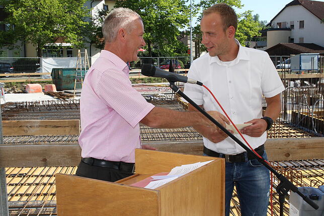 Dank an die Bauarbeiter: Bürgermeister Manfred Härle (links) übergibt Bauleiter Marc Krämer von der Firma Hebel bei der Grundsteinlegung ...